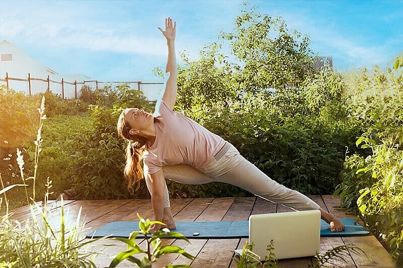 Frau praktiziert Ypoga per Online Yoga im Freien.