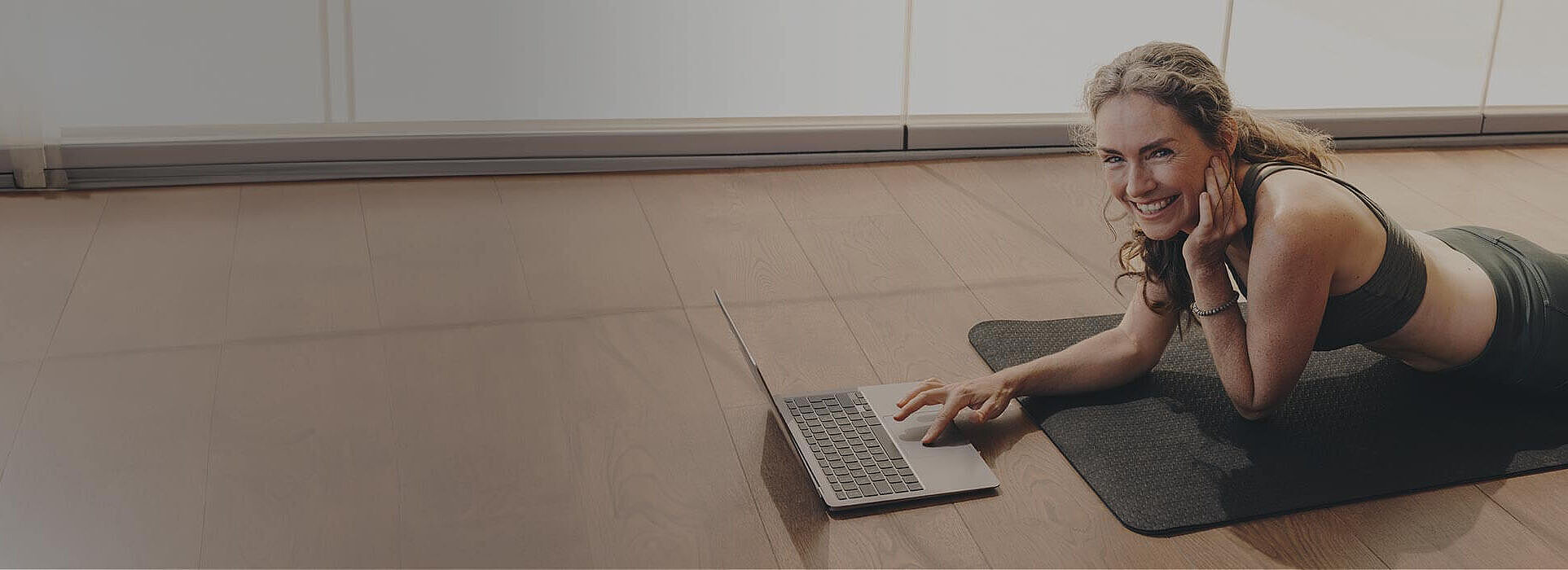 Frau beim Online Yoga mit Laptop