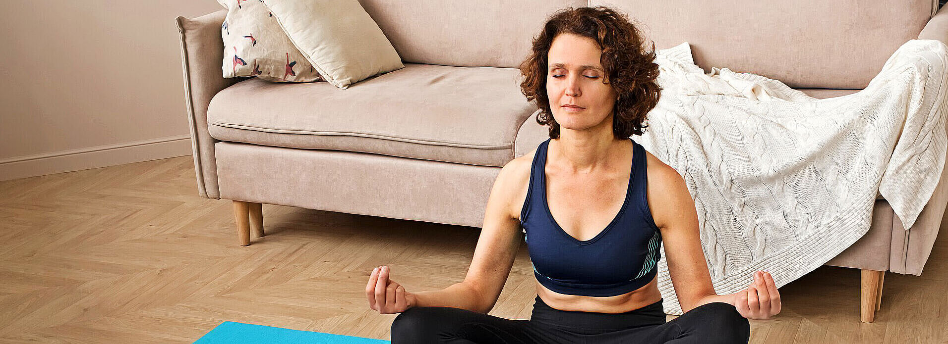 Yoga für Anfänger - Frau meditiert Zuhause