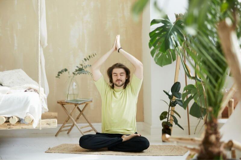 Atemübung für mehr Energie | Mann im Meditationssitz hebt die Arme